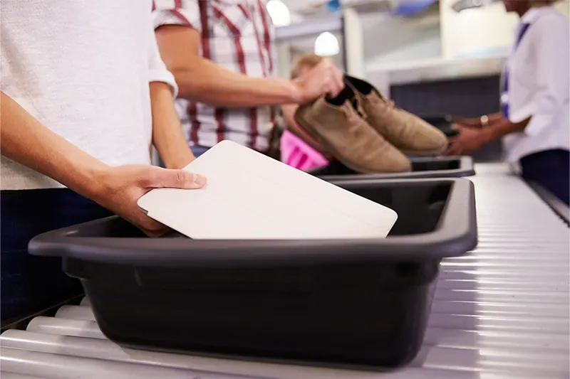 Person putting tablet in bin at airport security